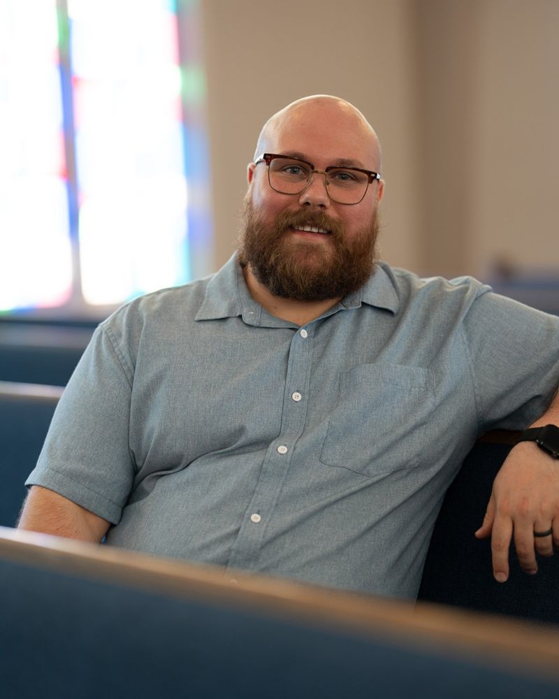 Pastor Phil Harden seated in a sanctuary pew